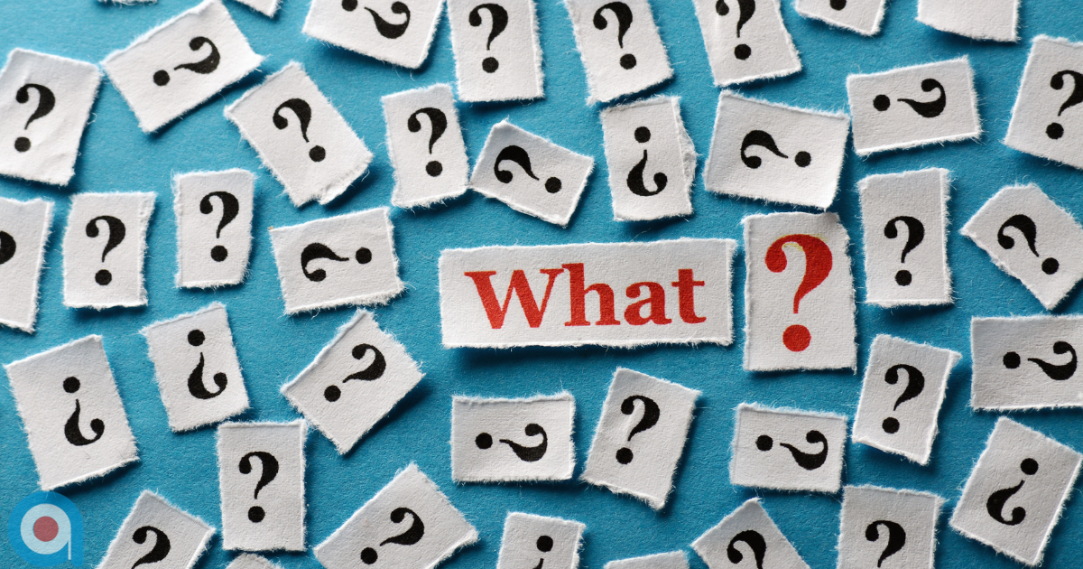 Blue background covered with scattered paper cutouts showing black question marks surrounding a central label reading “What?” in red text, representing confusion, uncertainty or questions.